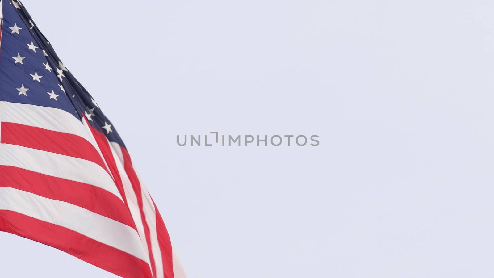 American flag waving in wind, USA. National symbol waves in breeze on flagpole. by DogoraSun