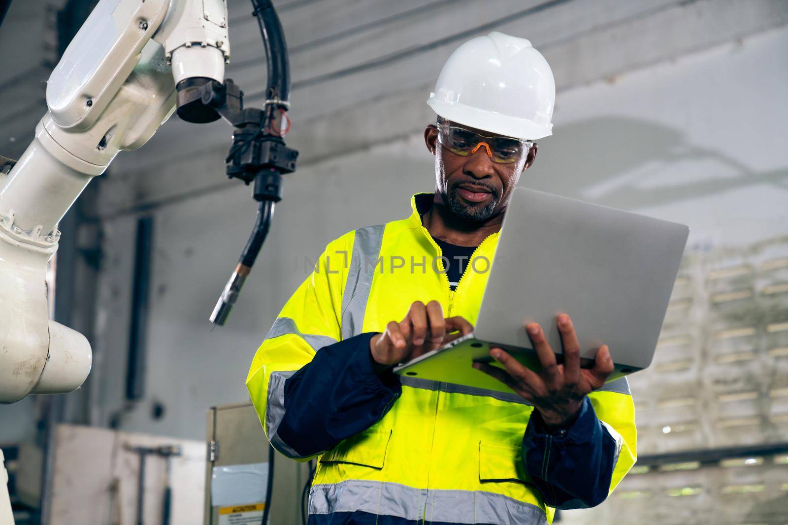 African American factory worker working with adept robotic arm in a workshop . Industry robot programming software for automated manufacturing technology .