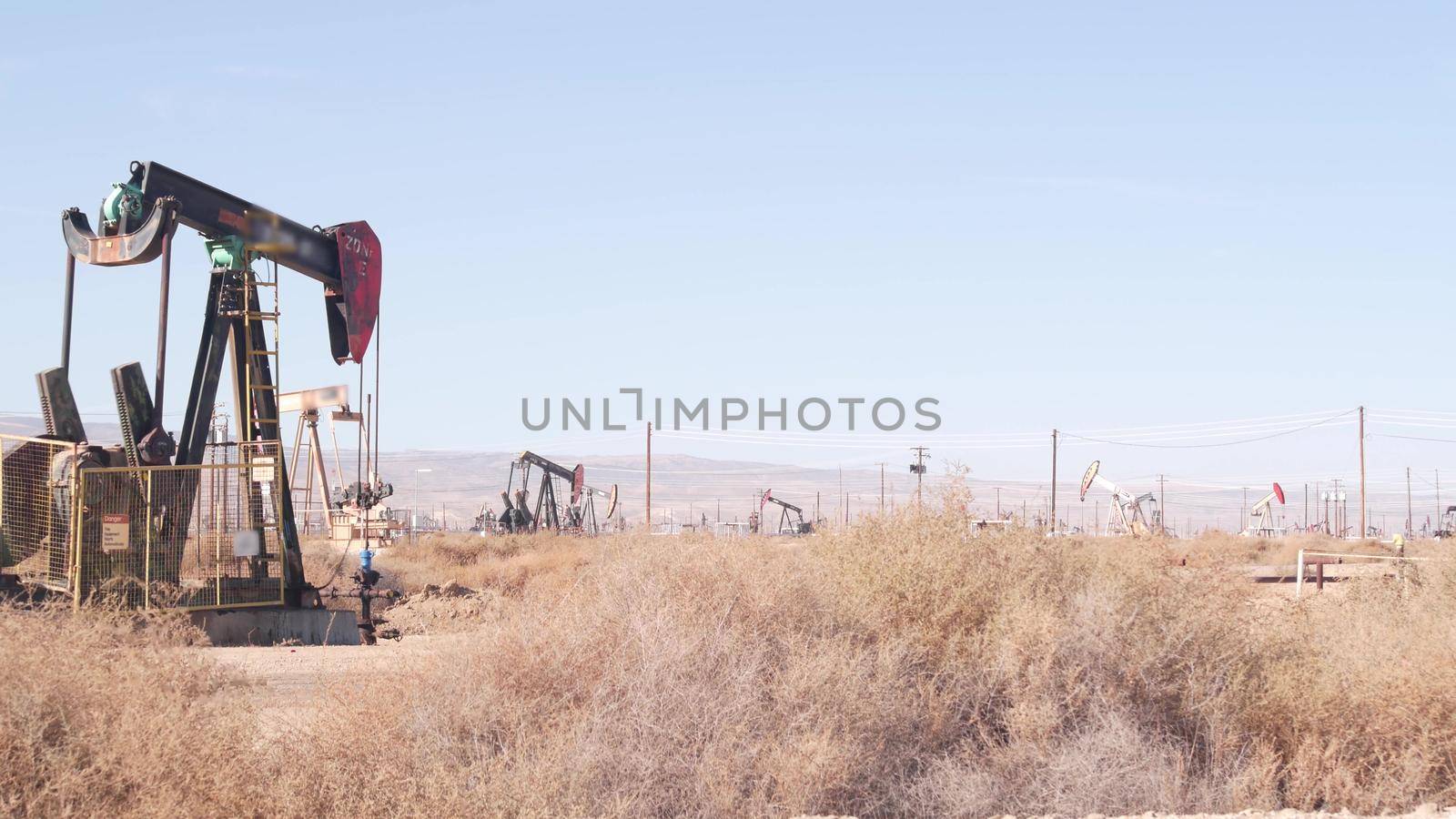 Pump jacks on oil field, USA. Rigs for crude fossil extraction on oilfield wells by DogoraSun