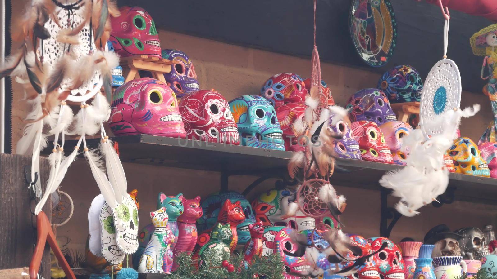 Mexican souvenirs on market stall, colorful painted skulls and dream catchers. Multicolor vivid ethnic ornaments, bazaar or marketplace. Ceramic crafted death symbol for sale on counter. Day of Dead.