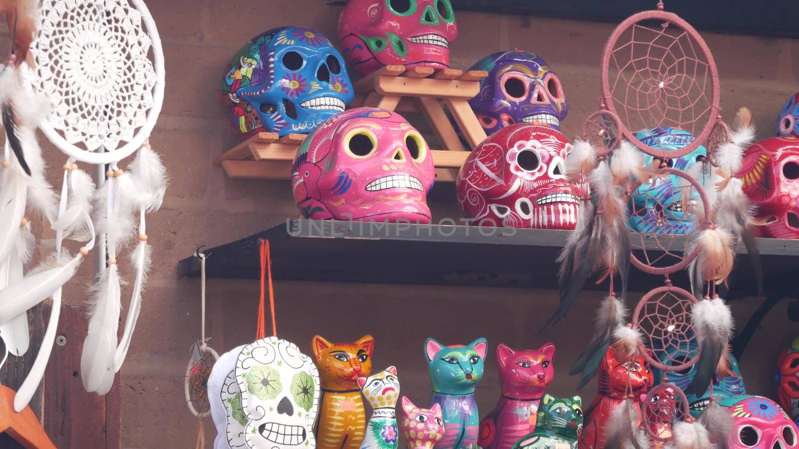 Mexican souvenirs on market stall, colorful painted skulls and dream catchers. Multicolor vivid ethnic ornaments, bazaar or marketplace. Ceramic crafted death symbol for sale on counter. Day of Dead.