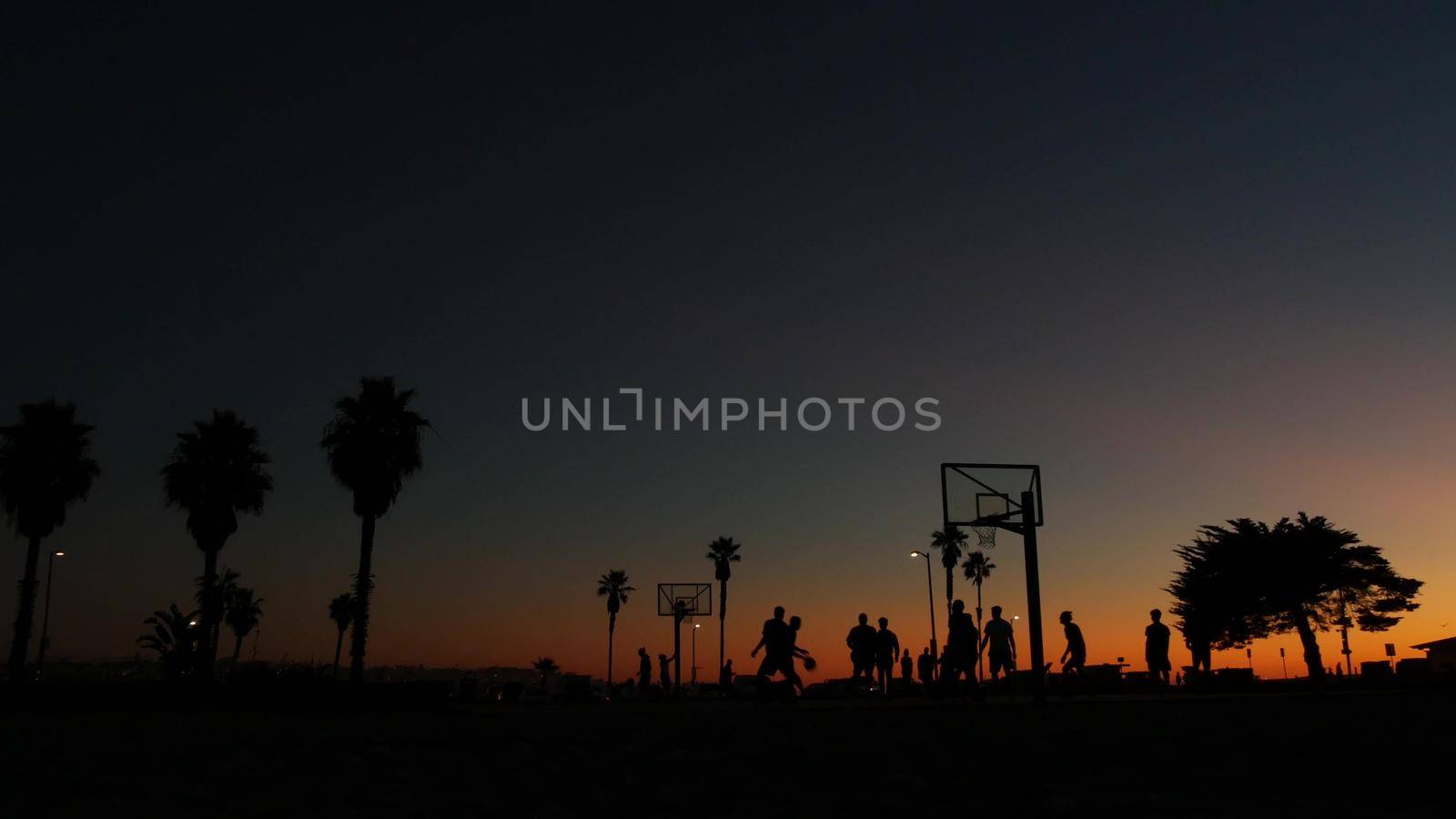 Players on basketball court playing basket ball game, sunset beach, California. by DogoraSun