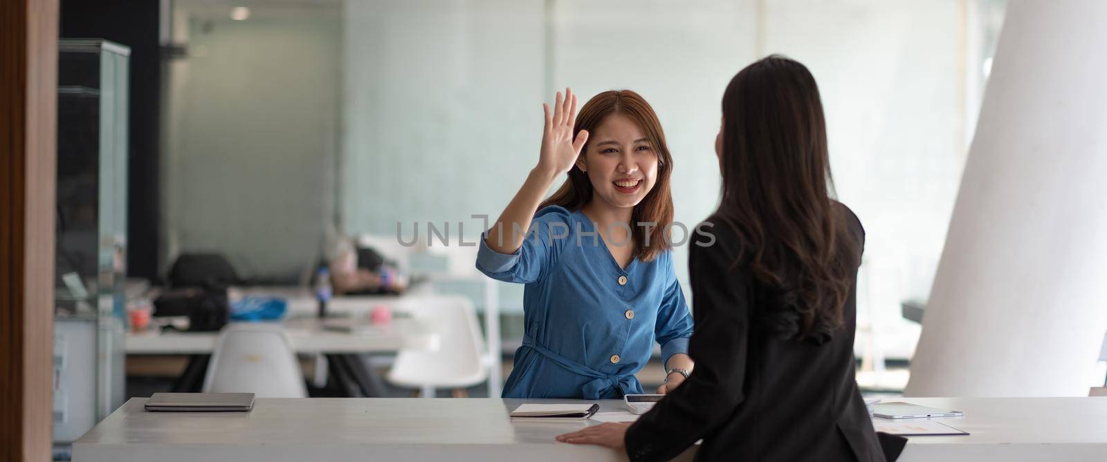 businesswomen giving hi five touching hands and thumb up during meeting for celebration business achievement and success with teamwork by nateemee