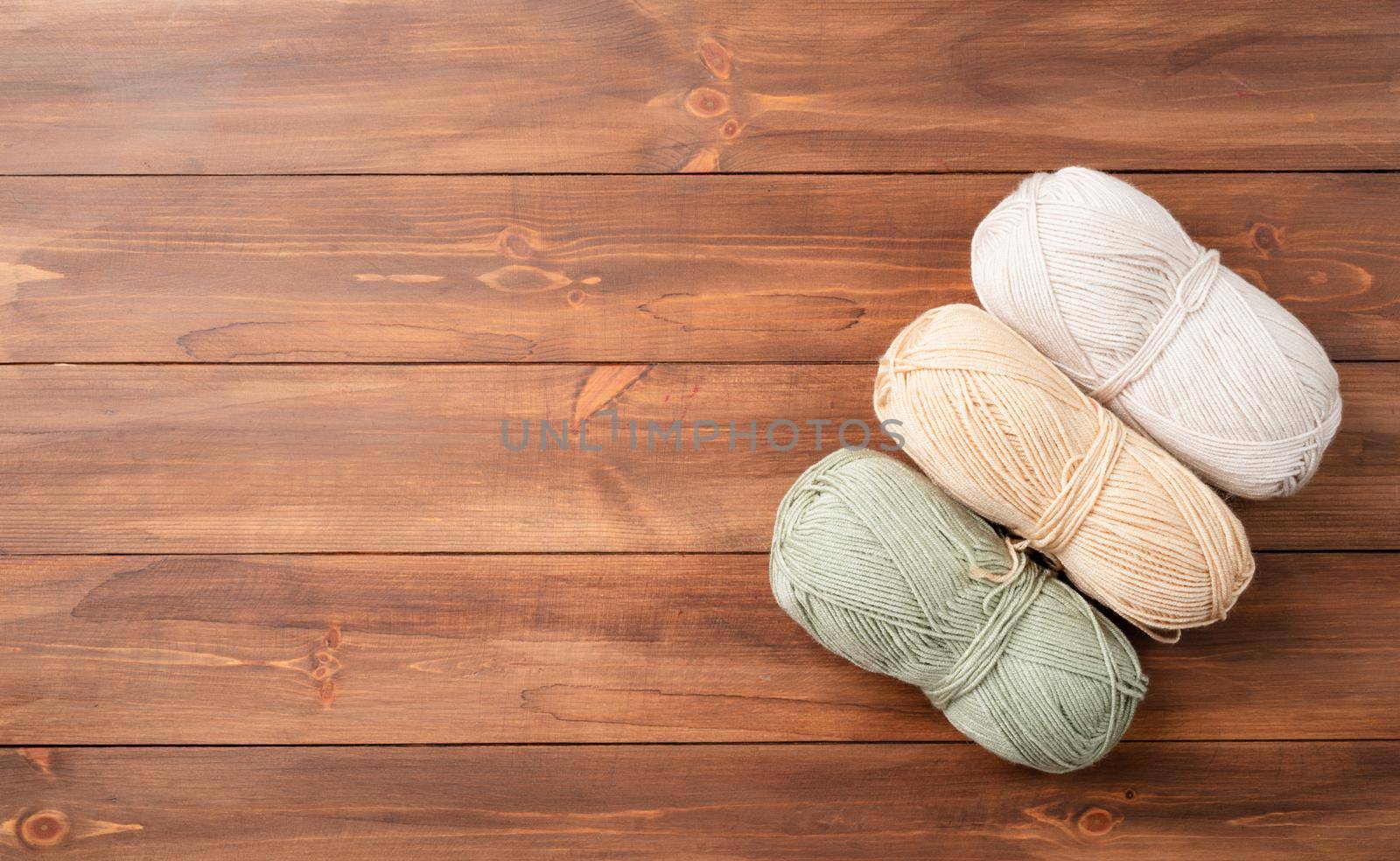 pastel colored yarn wool on wooden background, top view. Hobbies and leisure. Eco friendly, zero waste