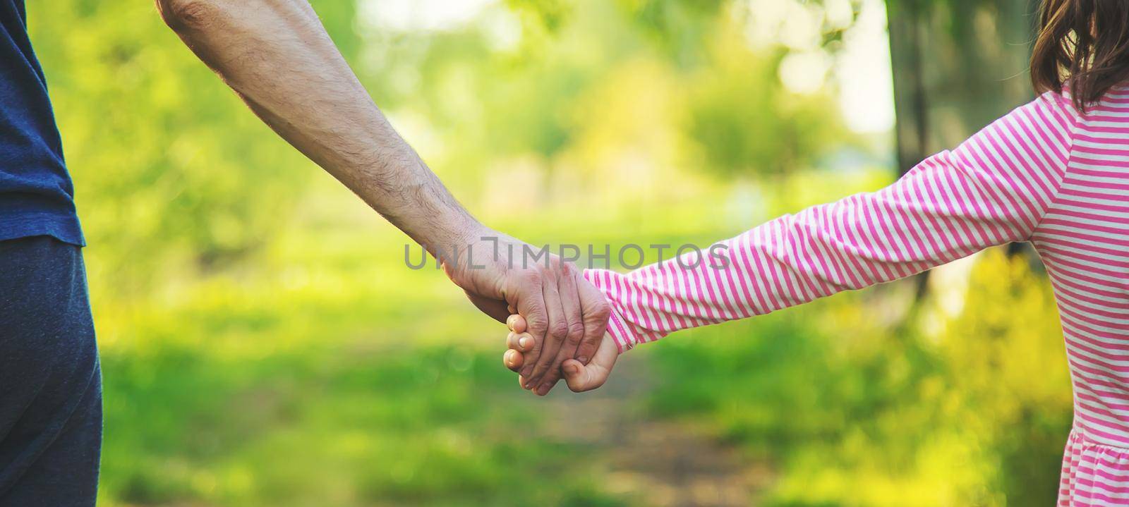 A child with his father goes by the hand. Selective focus by yanadjana
