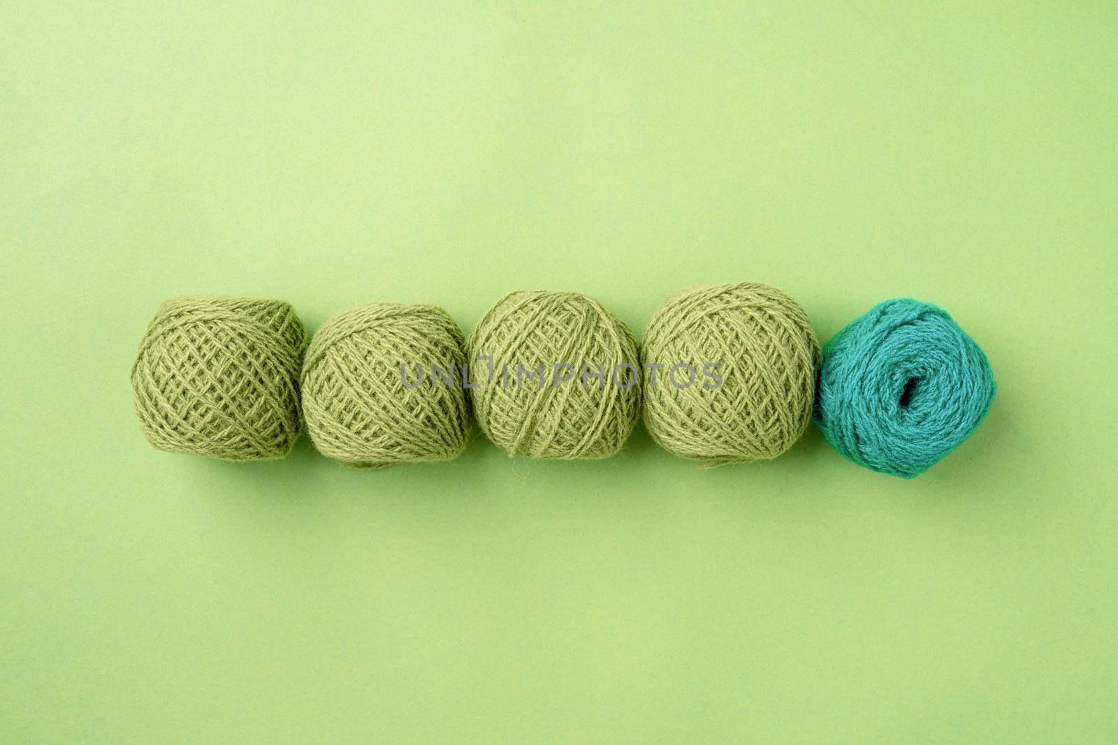 bright green yarn wool in a raw on green background, top view flat lay