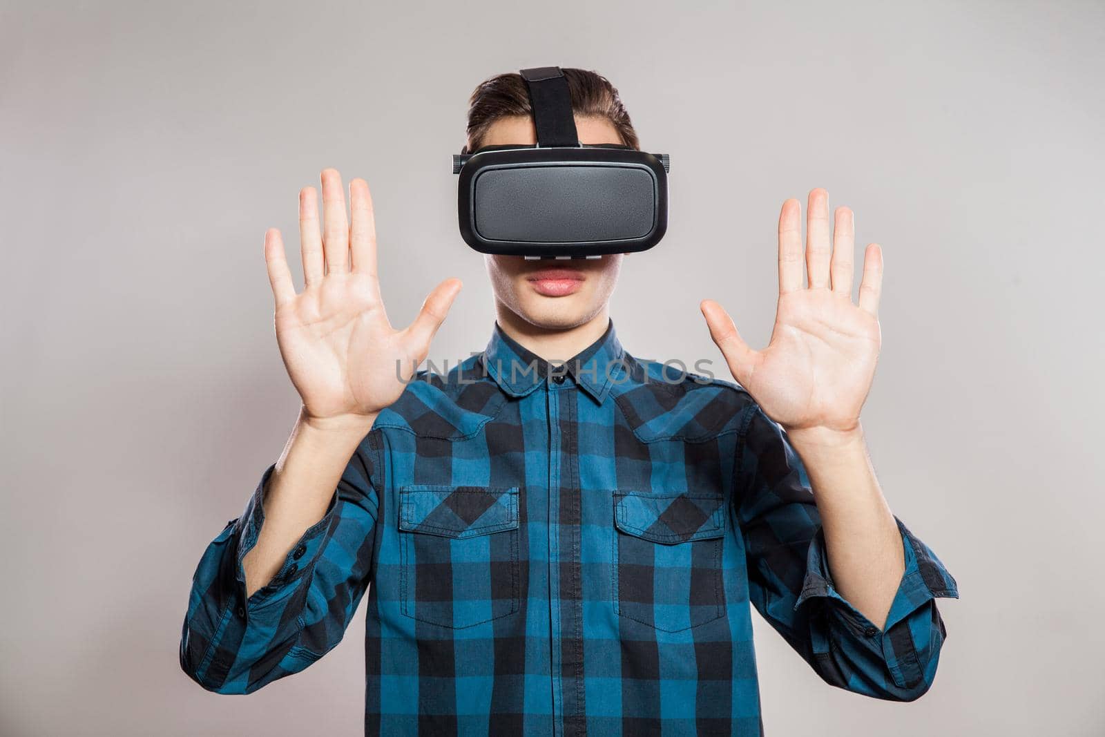 Portrait of young man with virtual reality headset. indoor, isolated on gray background.
