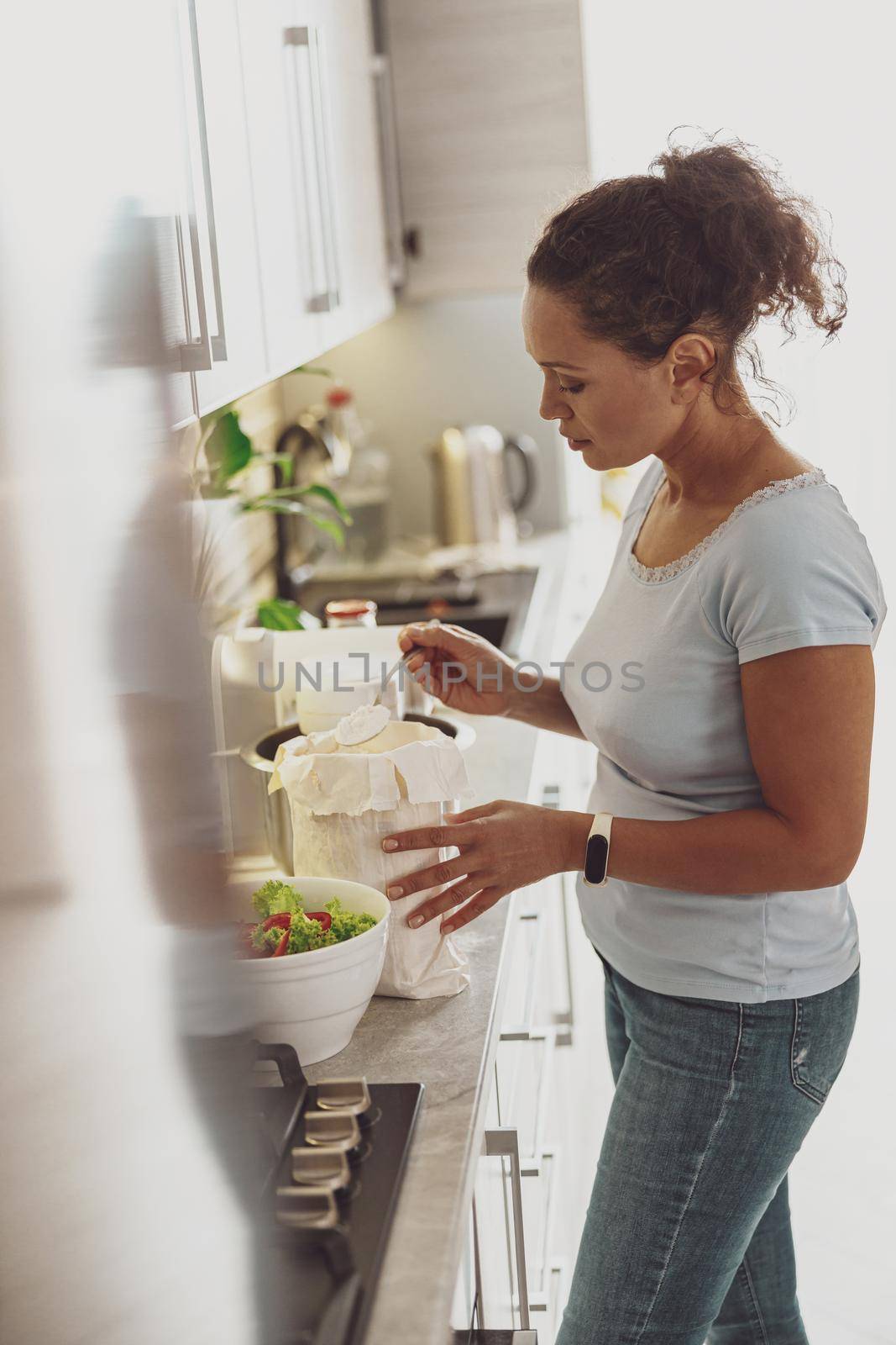 Cooking in the kitchen. A woman with a spoonful of flour in her hand prepares a dough