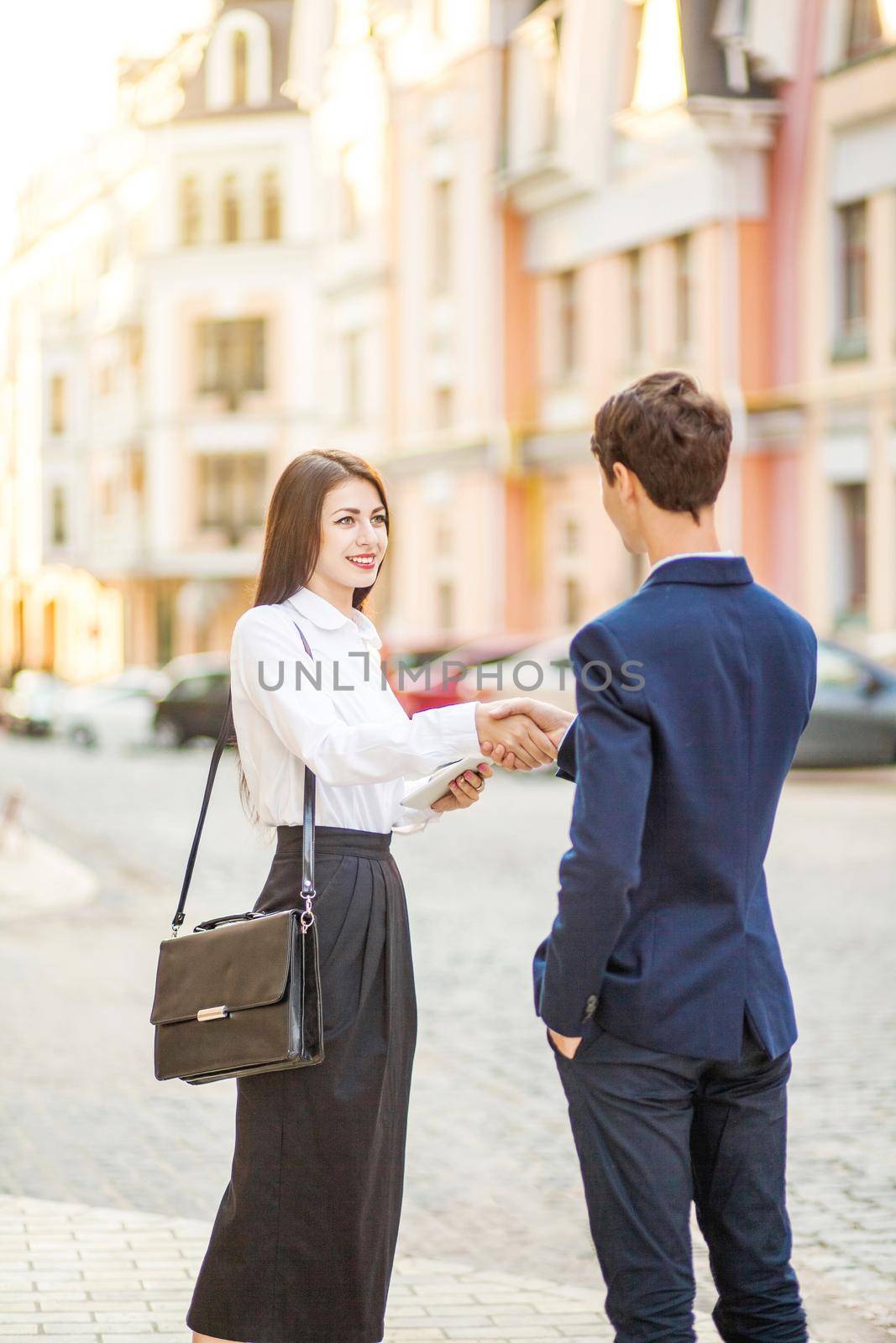 Business, partnership, technology and people concept - smiling businessman and businesswomen handshake for a business meeting outdoor..