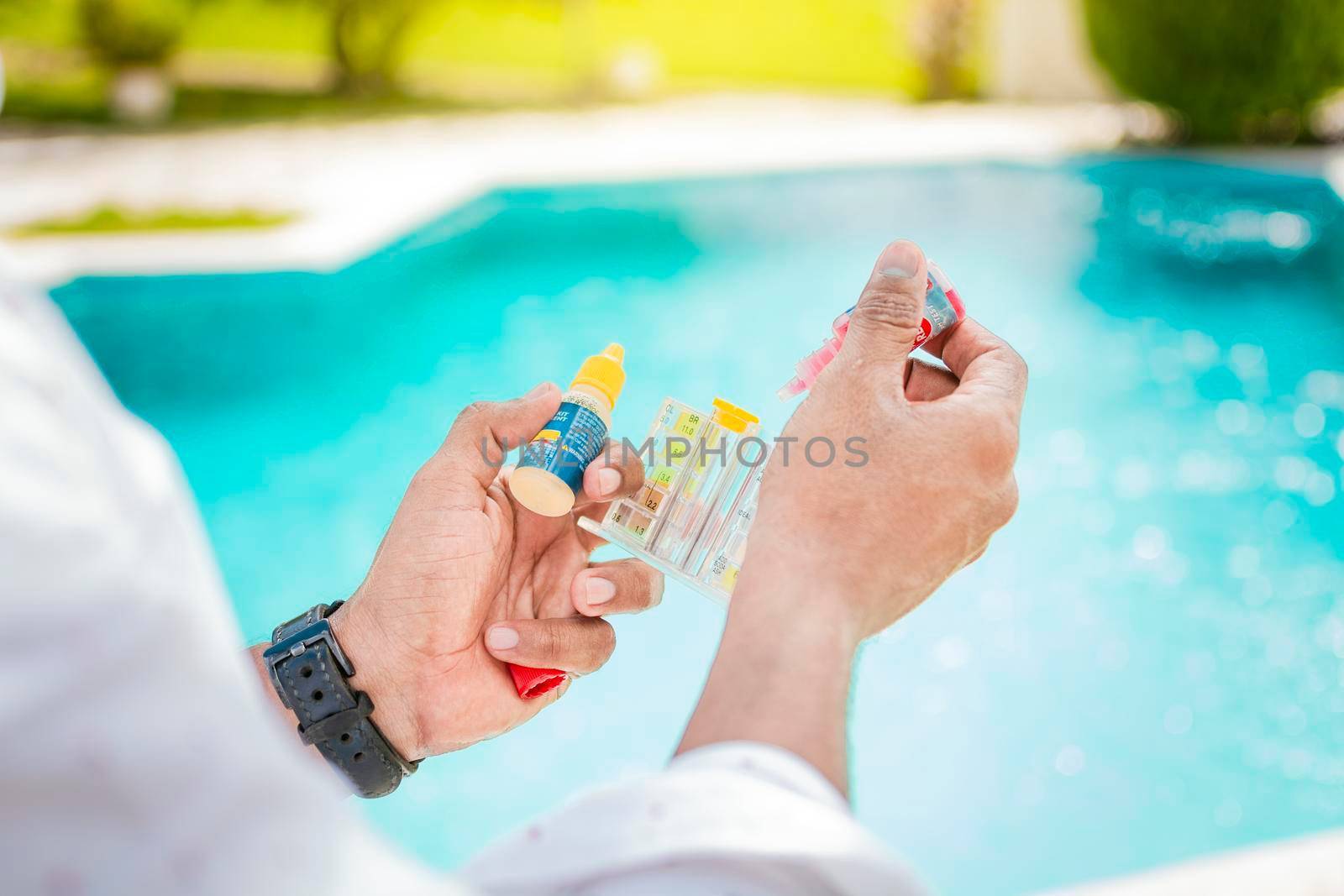 Hand holding a pool ph and chlorine tester, Hand holding Water Test Kit on blurred pool background, Person holding complete water test kit with blurred pool background