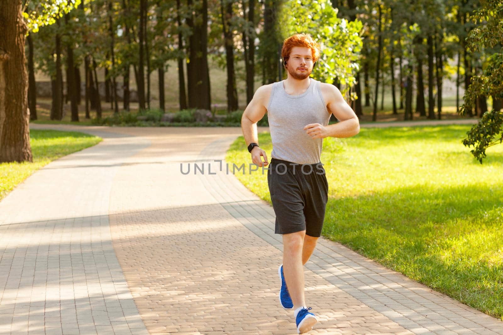 Runner in park. Young athletic man jogging at morning. Fitness model in crossfit exercise outdoors. Healthy lifestyle concept.