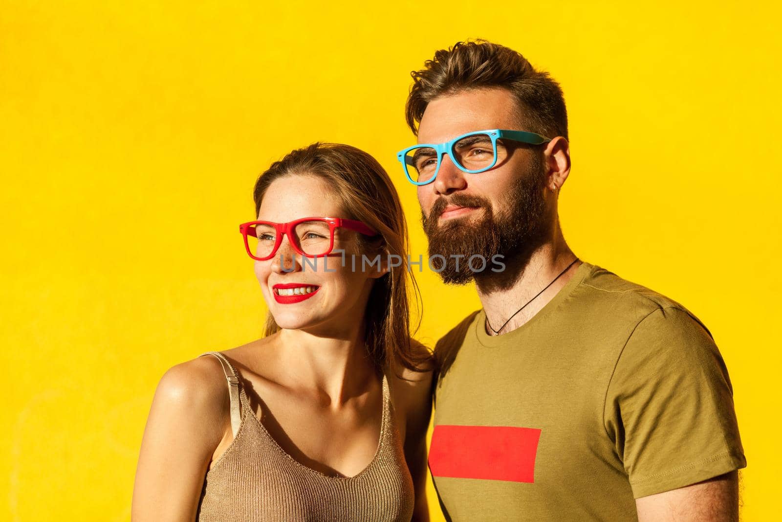 Happiness hipster friends, looking away and smiling. Indoor, studio shot on yellow background