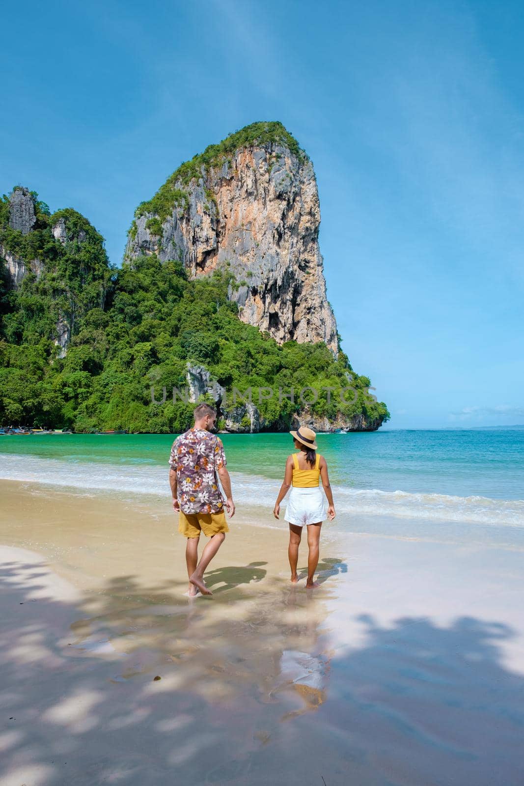 Railay Beach Krabi Thailand, the tropical beach of Railay Krabi, a couple of men and woman on the beach, Panoramic view of idyllic Railay Beach in Thailand with a traditional long boat.