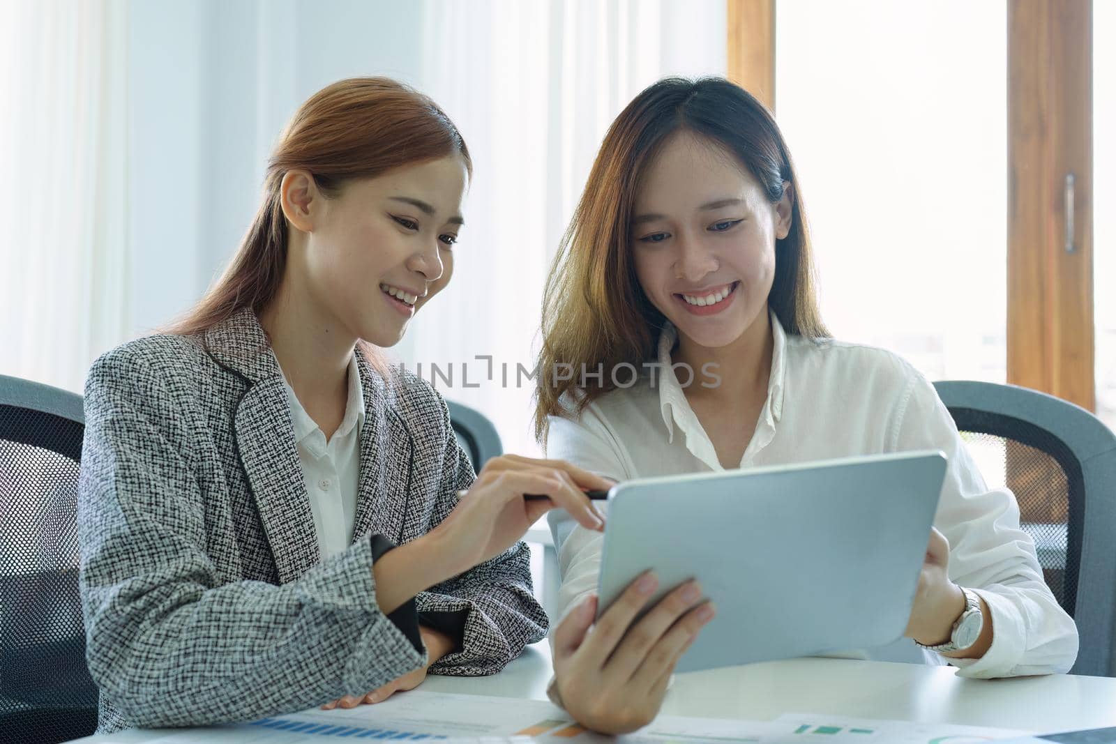 young Asian businesswoman using tablet computers to plan marketing strategies and invest to profit from customers.