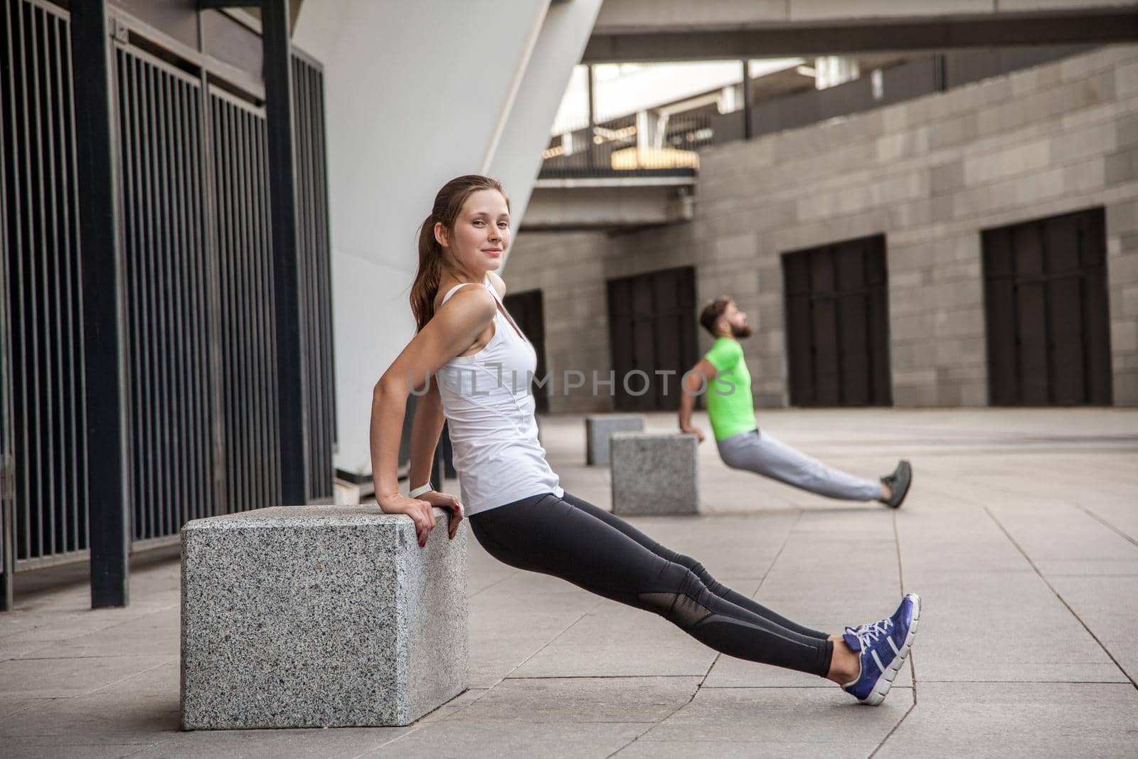 fitness, sport, exercising, training and people concept - couple doing triceps dip exercise on city street bench.