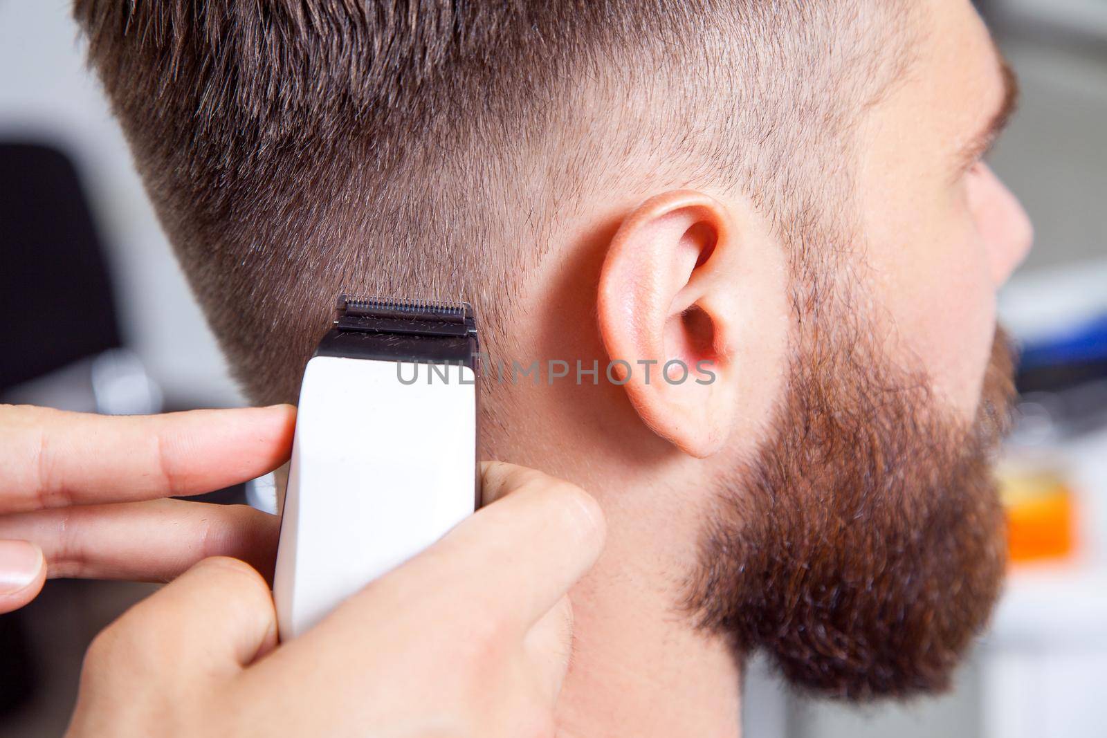 Barber cutting and modeling hair by electric trimmer..
