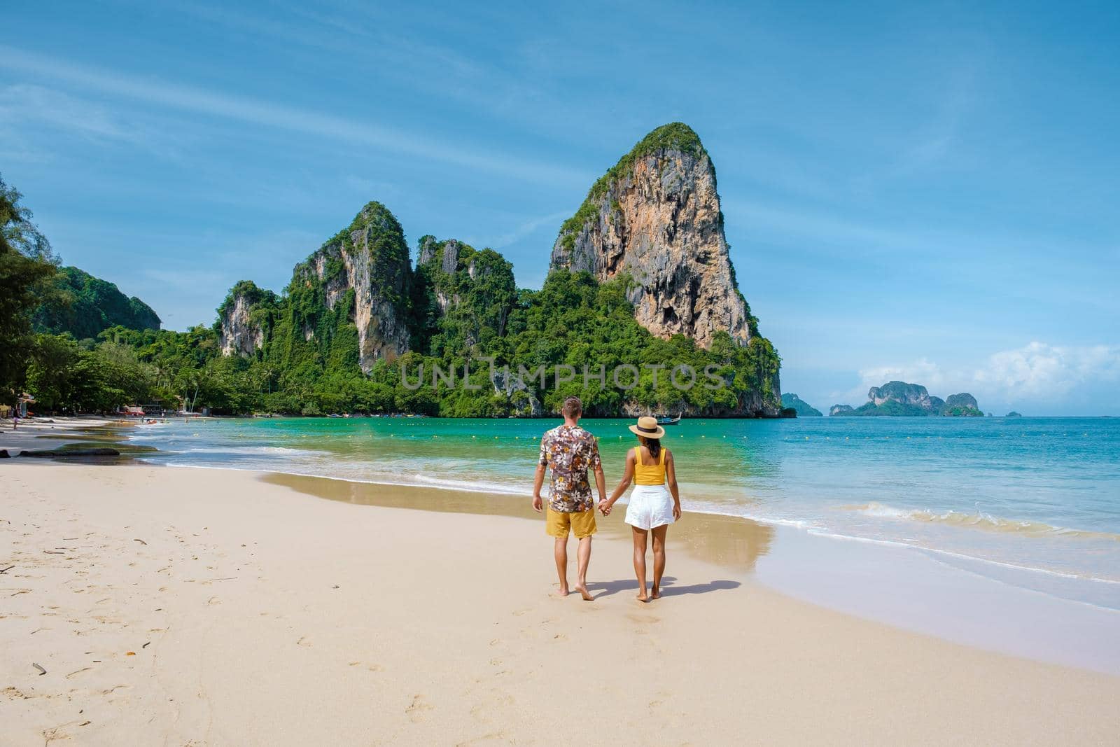 Railay Beach Krabi Thailand, the tropical beach of Railay Krabi, a couple of men and woman on the beach, Panoramic view of idyllic Railay Beach in Thailand with a traditional long boat.