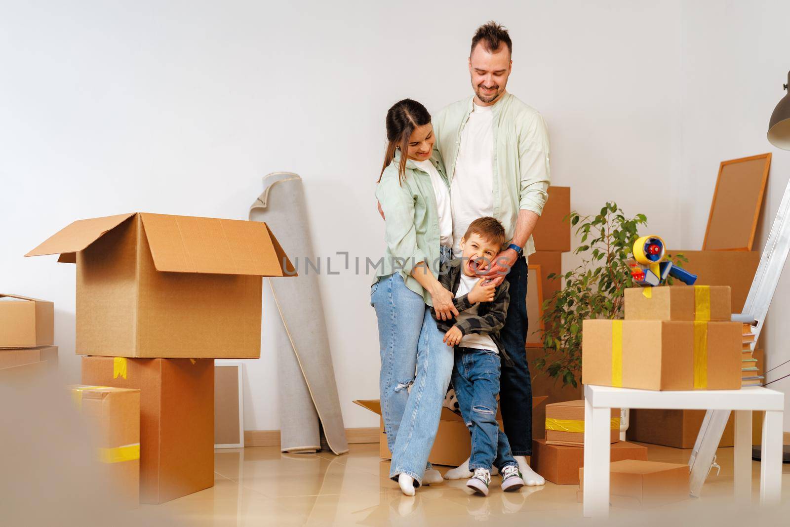 Young parents and son having fun during moving day to new house, portrait