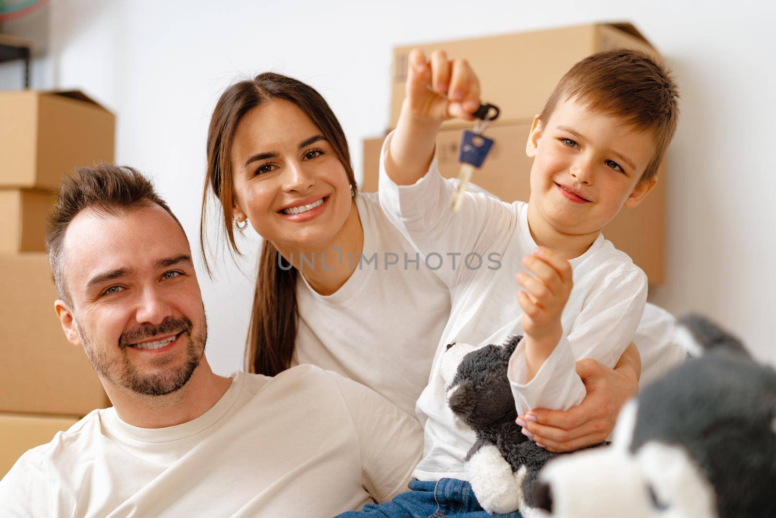 Portrait of happy family with cardboard boxes in new house at moving day by Fabrikasimf