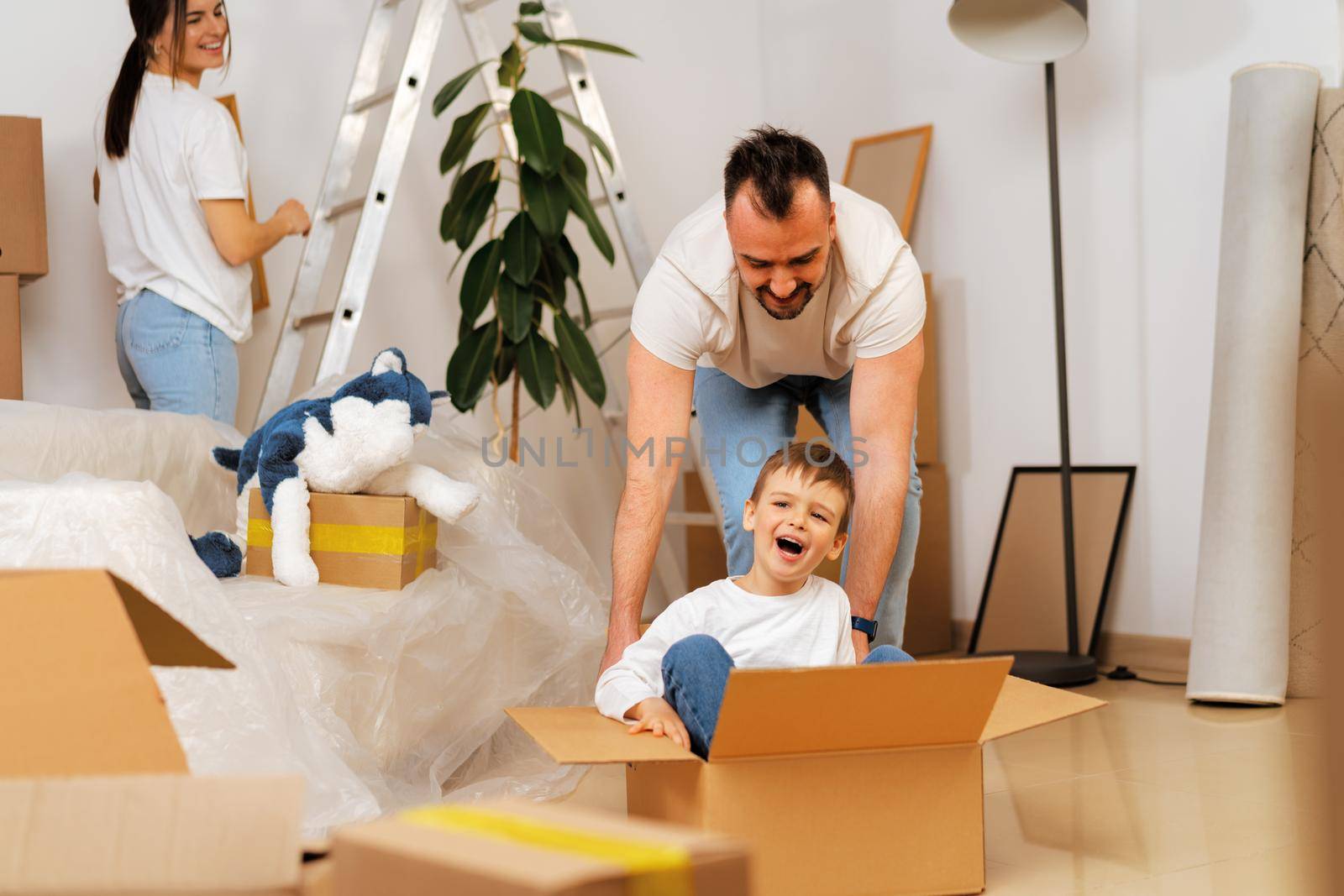 Parents and son packing boxes and moving into a new home having fun
