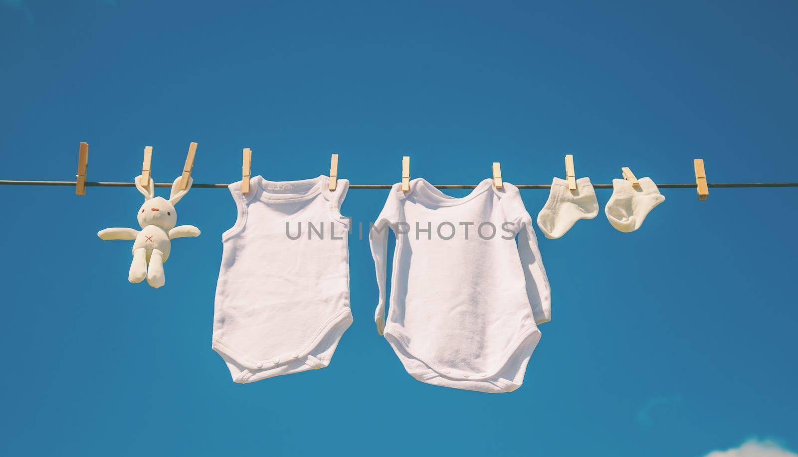 White baby clothes dry on a rope. Selective focus. by yanadjana