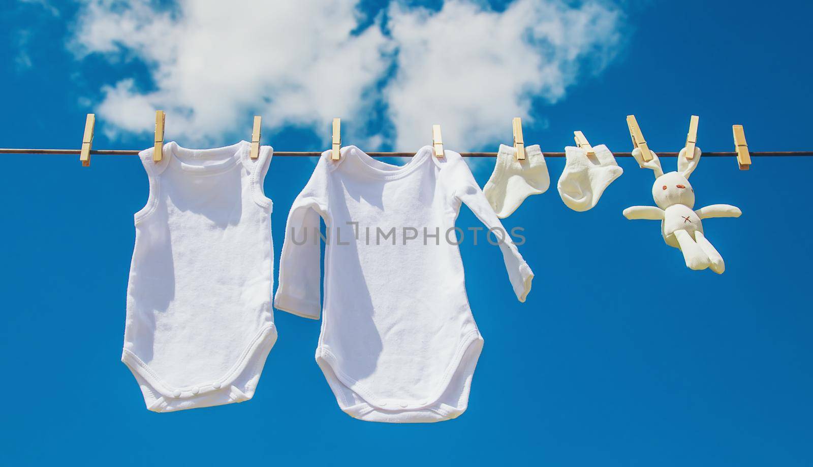 White baby clothes dry on a rope. Selective focus. by yanadjana