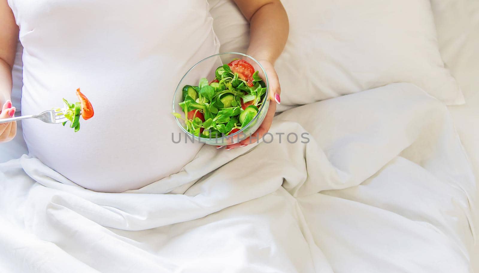 A pregnant woman eats a salad with vegetables. Selective focus. Food.