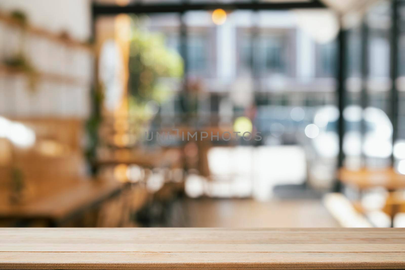 Empty wooden table in front of blurred background of coffee shop. Copy space for display or montage your products. by prathanchorruangsak