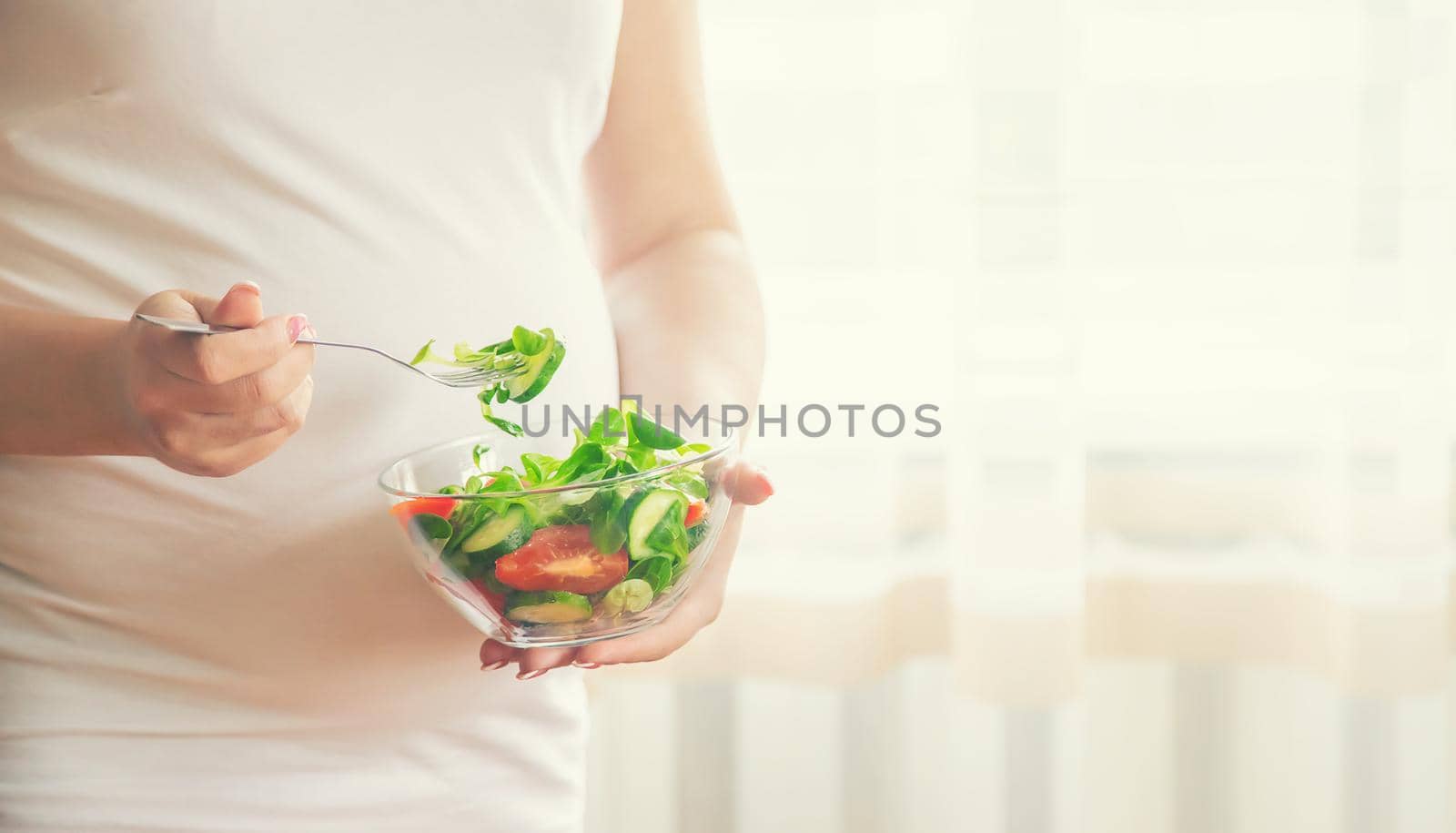 A pregnant woman eats a salad with vegetables. Selective focus. by yanadjana