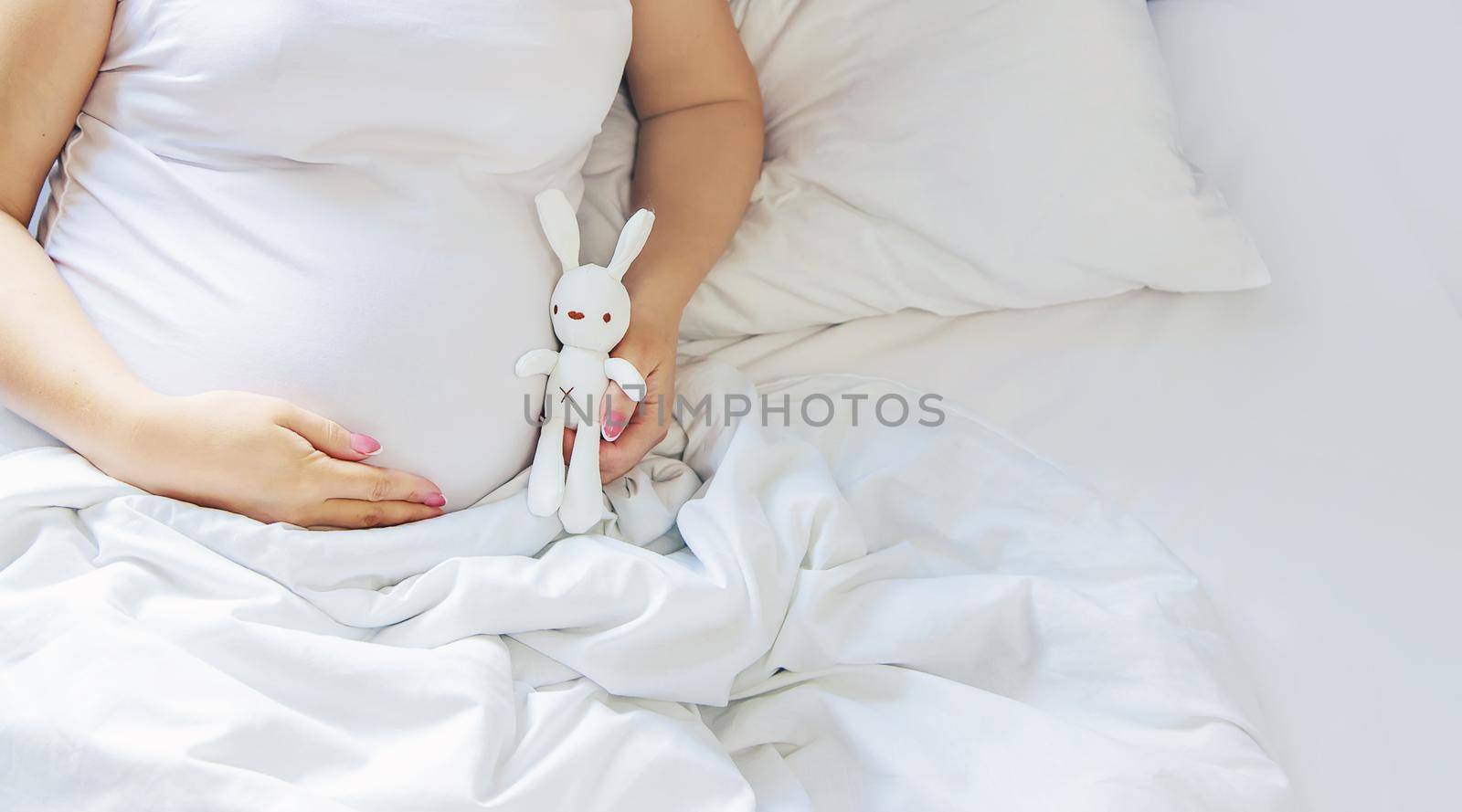 A pregnant woman hugs her belly with a toy. Selective focus. by yanadjana