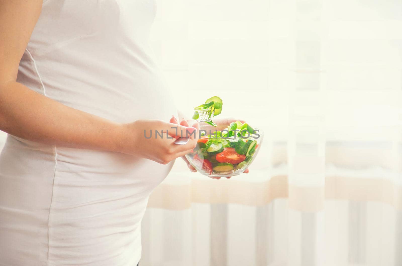 A pregnant woman eats a salad with vegetables. Selective focus. Food.