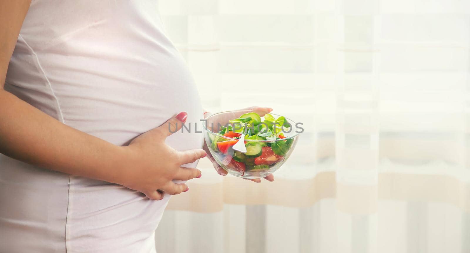 A pregnant woman eats a salad with vegetables. Selective focus. by yanadjana