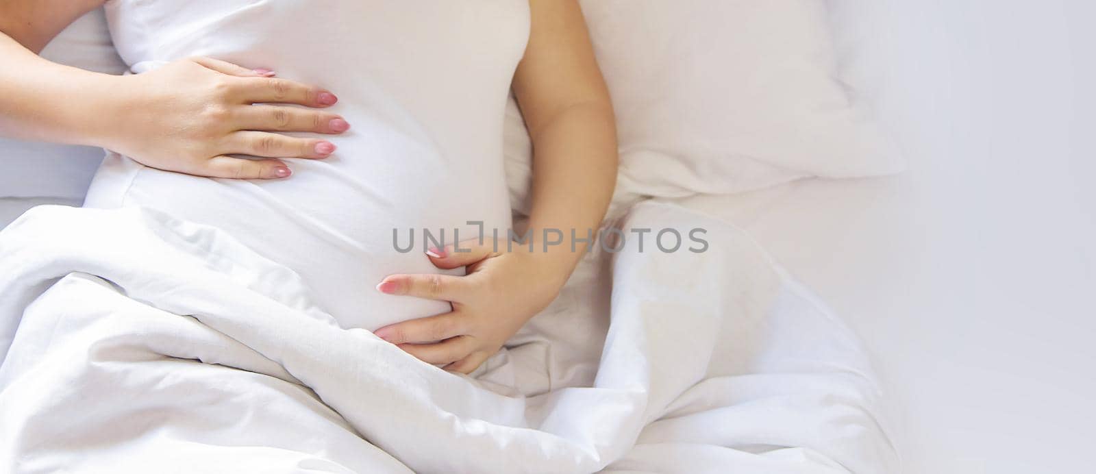 A pregnant woman hugs her belly. Selective focus. by yanadjana