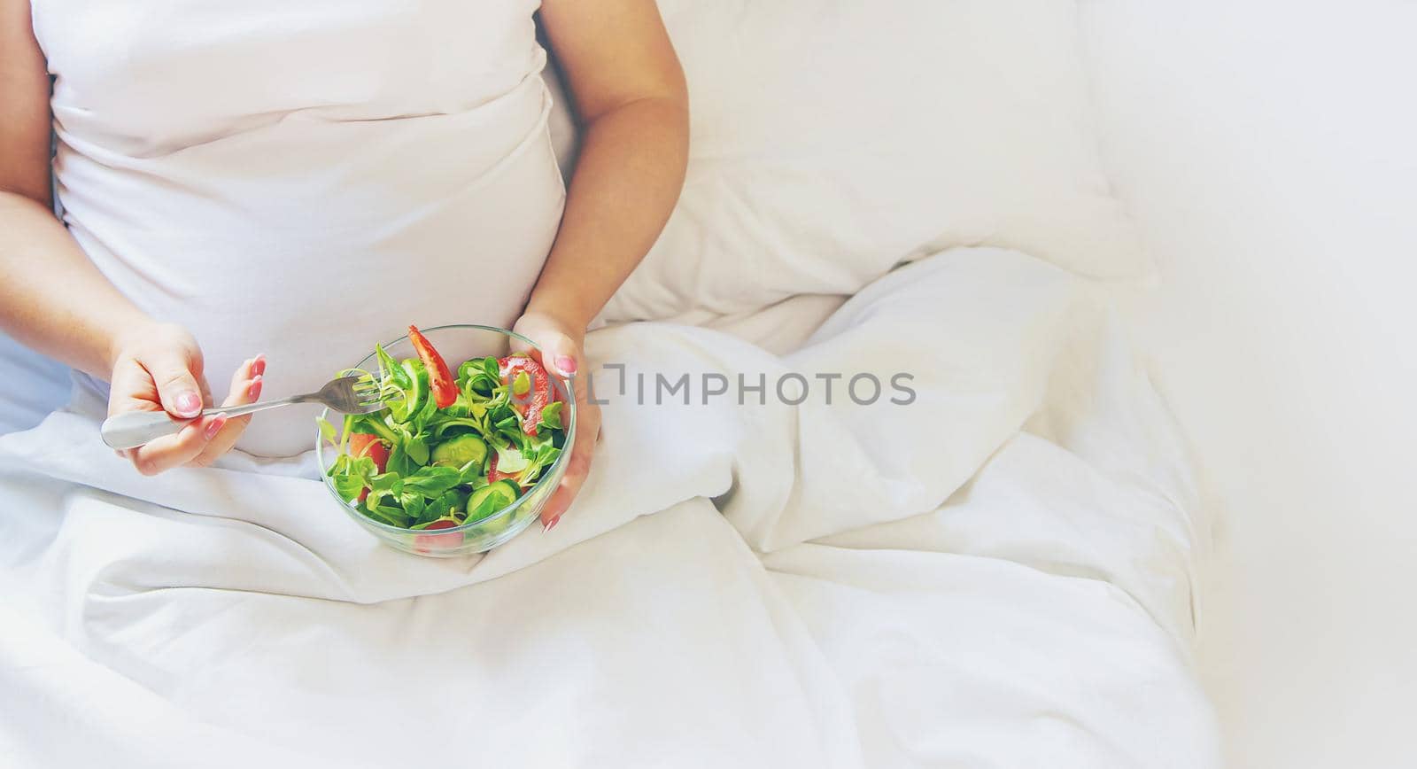 A pregnant woman eats a salad with vegetables. Selective focus. Food.