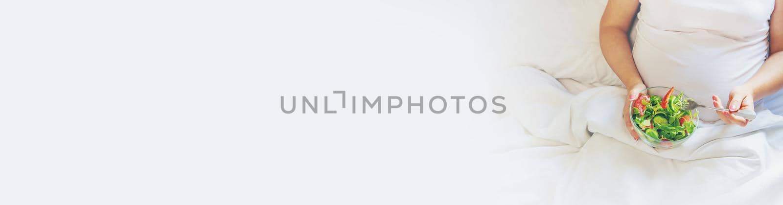 A pregnant woman eats a salad with vegetables. Selective focus. Food.