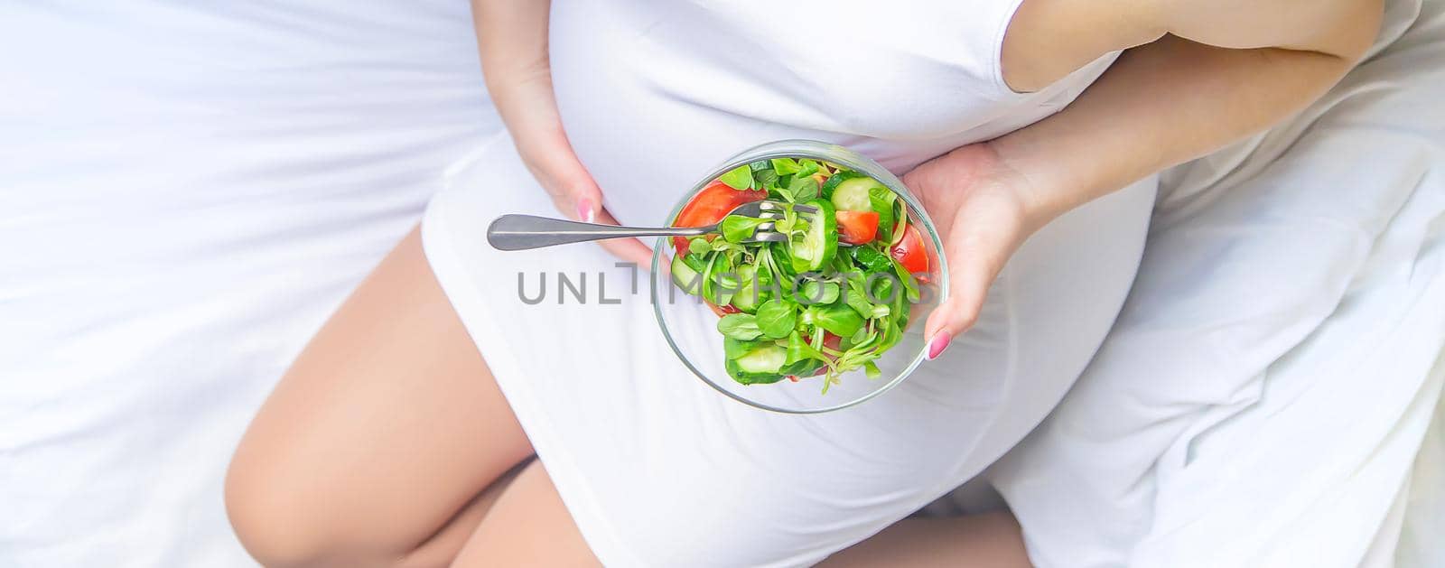 A pregnant woman eats a salad with vegetables. Selective focus. Food.