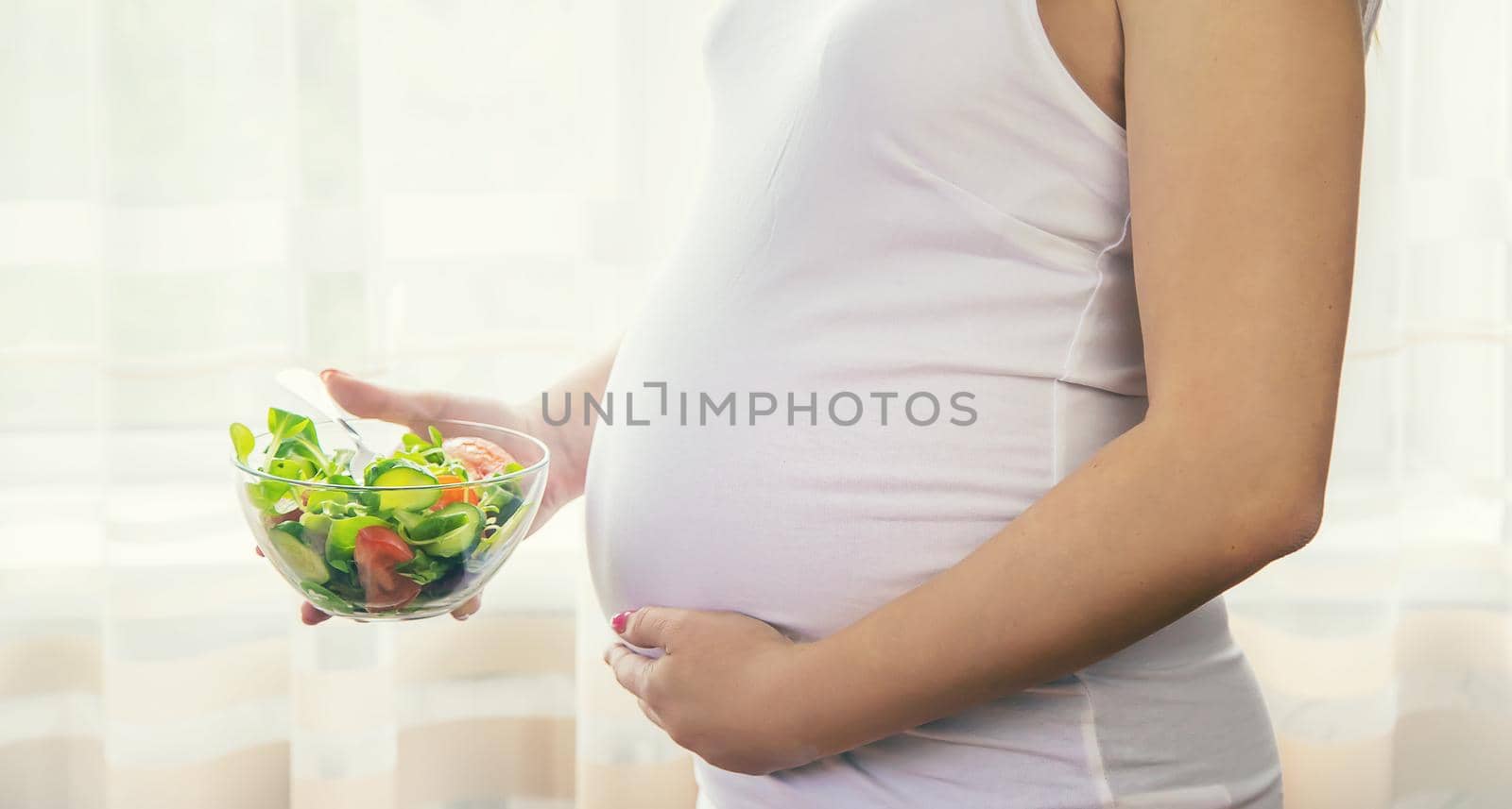 A pregnant woman eats a salad with vegetables. Selective focus. by yanadjana