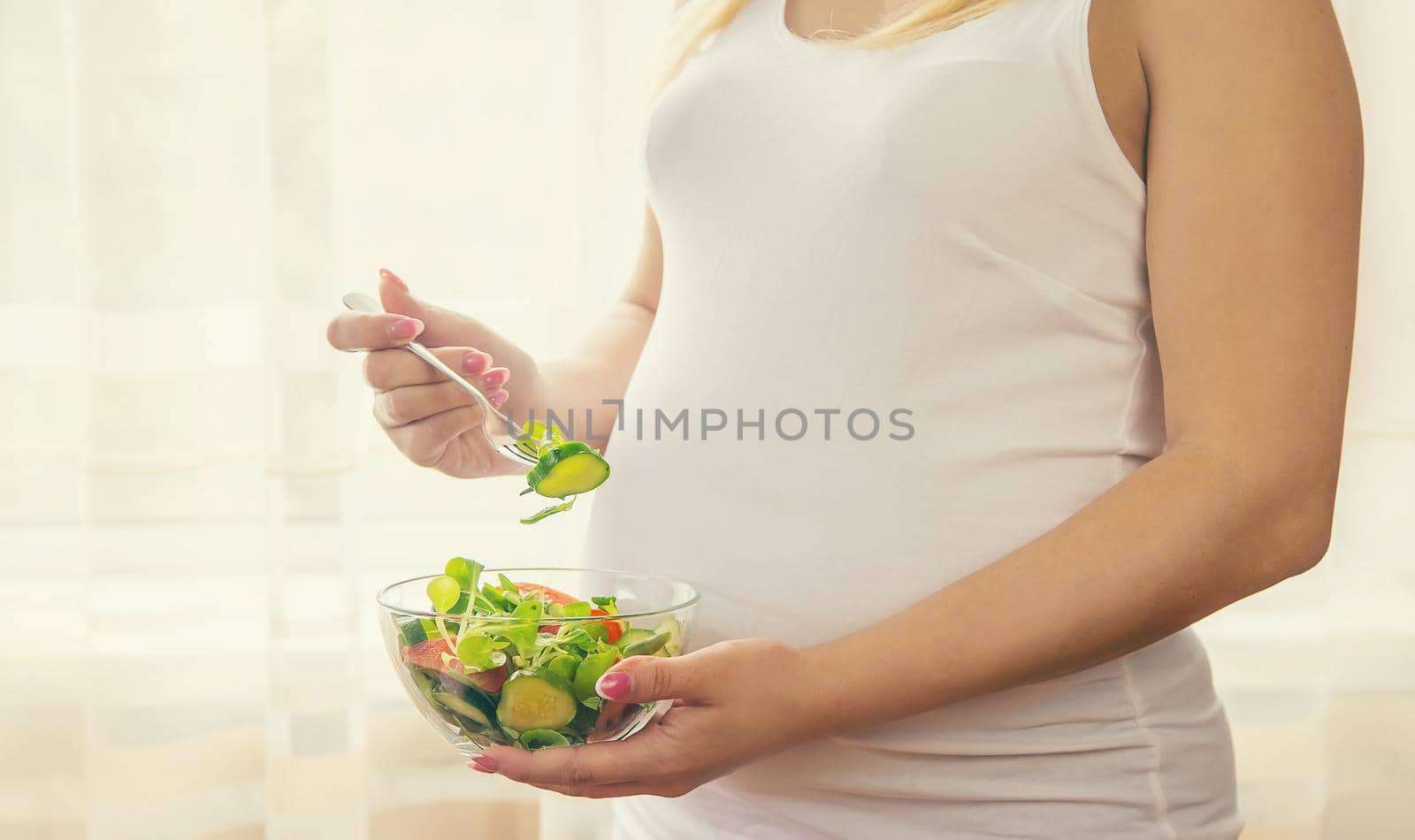 A pregnant woman eats a salad with vegetables. Selective focus. Food.