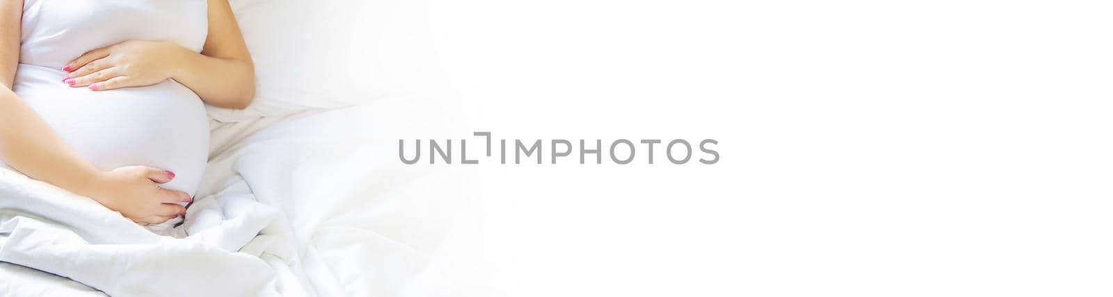 A pregnant woman hugs her belly. Selective focus. People.