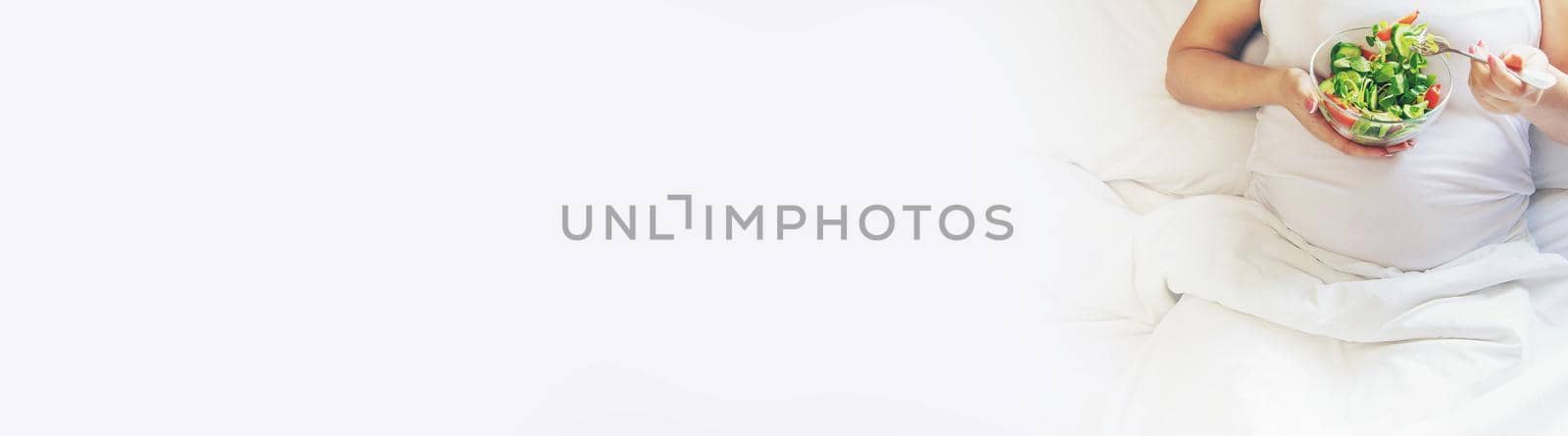 A pregnant woman eats a salad with vegetables. Selective focus. Food.