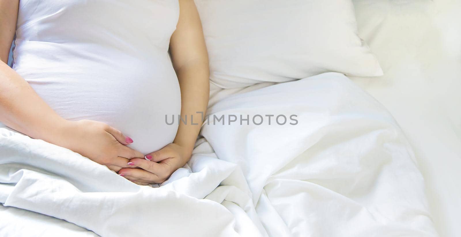 A pregnant woman hugs her belly. Selective focus. People.