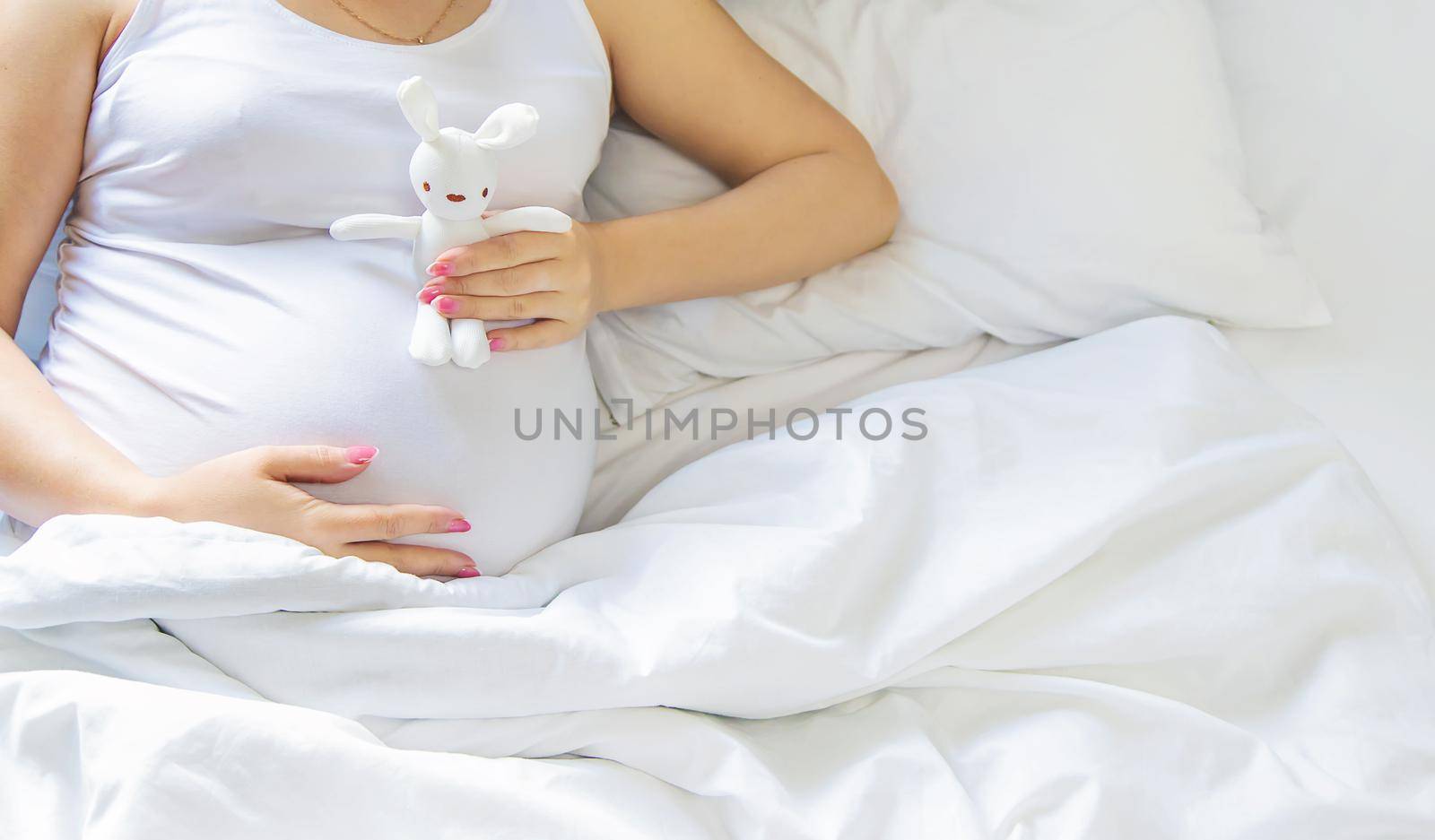 A pregnant woman hugs her belly with a toy. Selective focus. People.