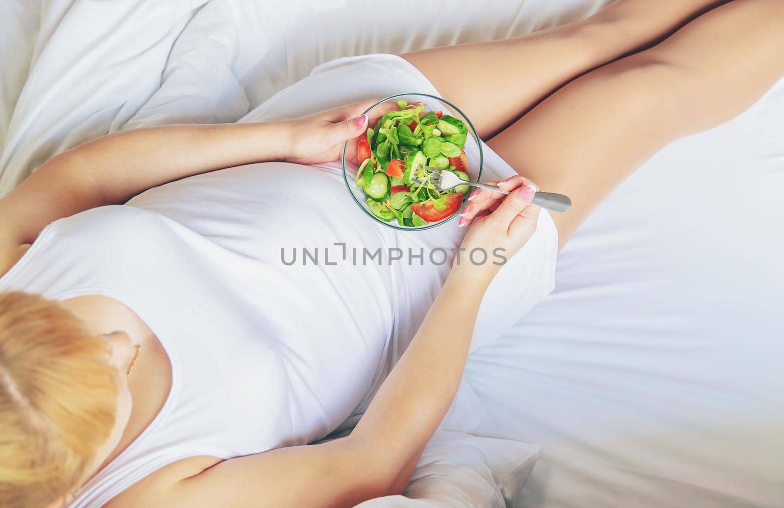A pregnant woman eats a salad with vegetables. Selective focus. Food.