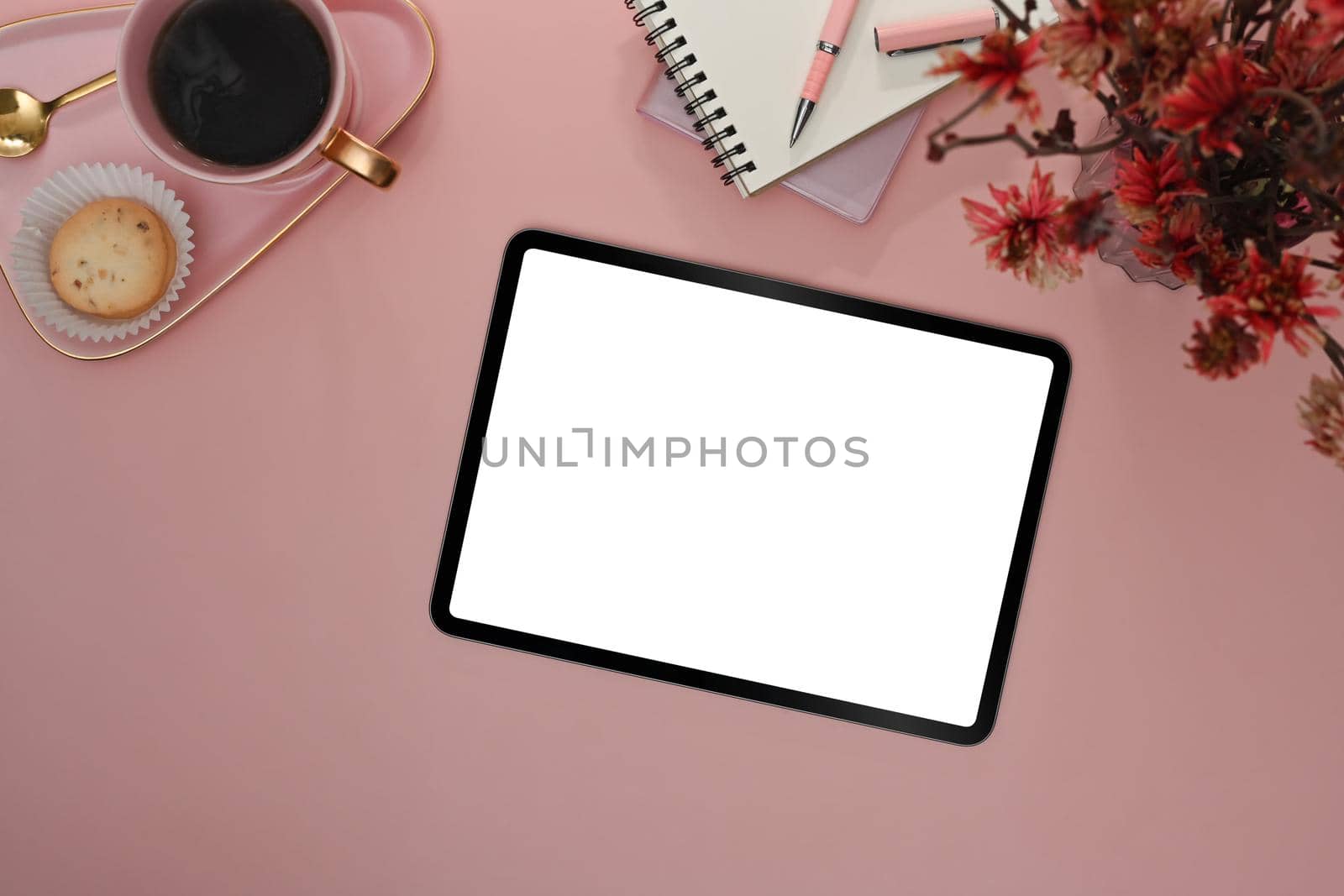 Flat lay digital tablet with blank screen, coffee cup and notebook on pink background.