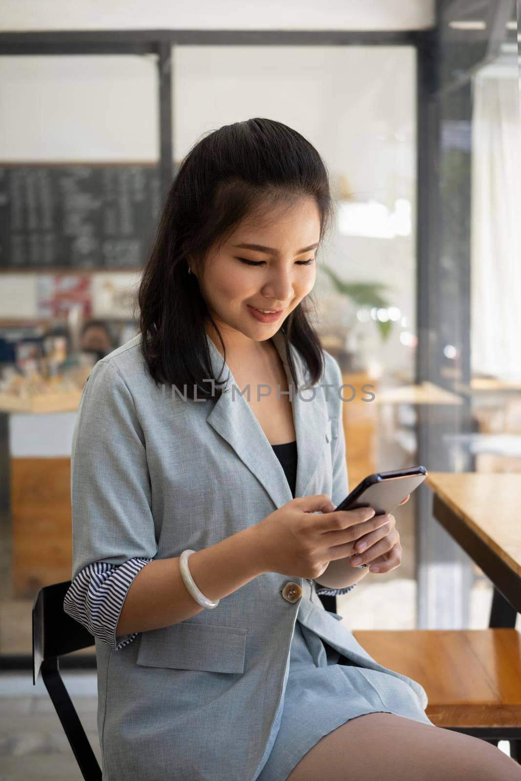 Pretty asian woman sitting in coffee shop and using smart phone.