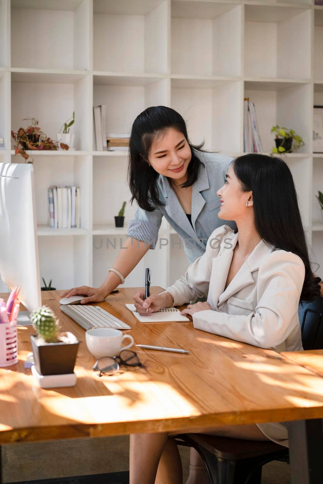 Two female financial workers sharing idea and working together at office. by prathanchorruangsak