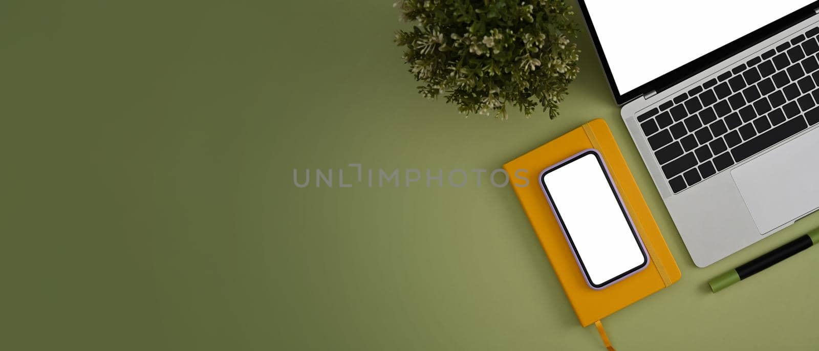 Top view mobile phone, laptop computer, notebook and houseplant on green background. by prathanchorruangsak