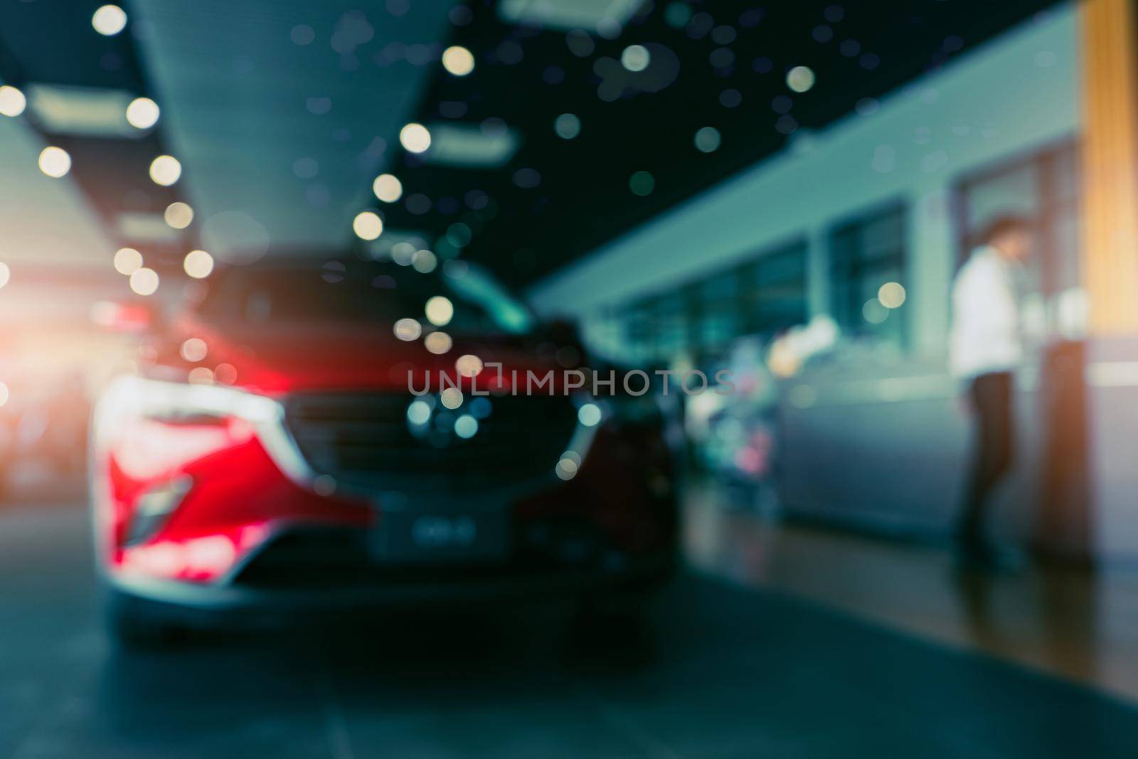 Blurred photo new red car parked in showroom. Car dealership office. Car parked in showroom with care. Auto for sale and rent business. Automobile leasing market. Electric vehicle. Luxury car company.