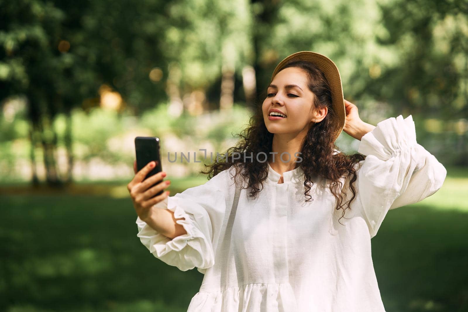 Young beautiful girl in a hat makes a selfie on her phone in the park. High quality photo