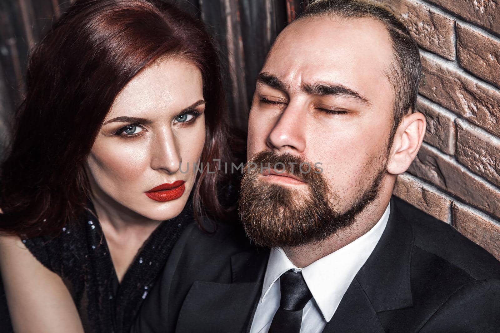 Passion concept, closeup. Bearded man closed eyes, redhead sensual woman with red lips and handsome makeup, looking at camera by Khosro1